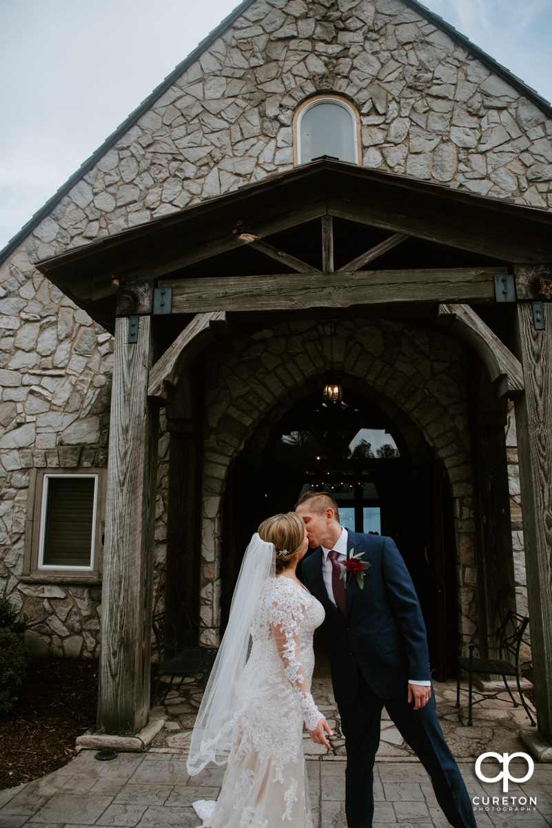 Bride and groom kissing outside of the chapel.