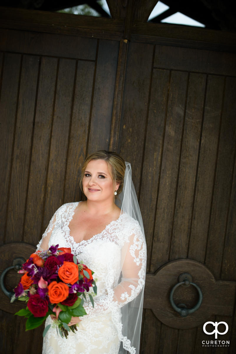 Bride in front of the double wooden doors at Glassy Chapel.
