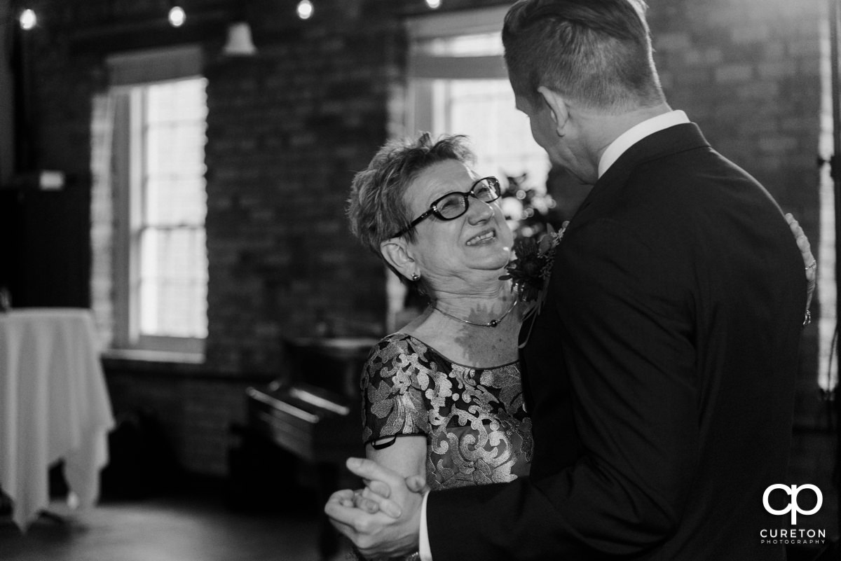 Groom's mom smiling at him during a dance at the reception.