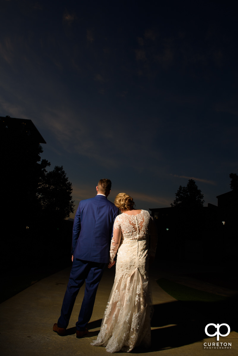 Bride laying her head on the groom's shoulder watching the sun set outside of their Larkin's Cabaret Room wedding reception.