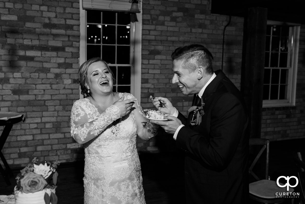 Bride and groom feeding each other cake.