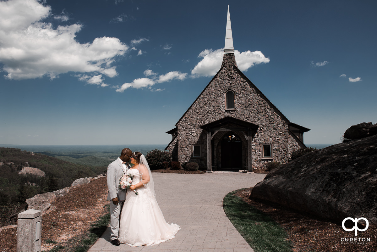 Bride and groom standing on a mountaintop after their wedding ceremony at the Cliffs Glassy Chapel.
