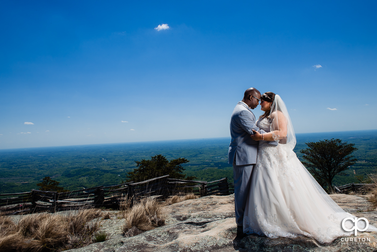 Bride and groom standing on top of a rock at the Cliffs at Glassy Chapel.