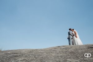 Bride and groom walking up a rock on a mountaintop at Cliffs Glassy Chapel.