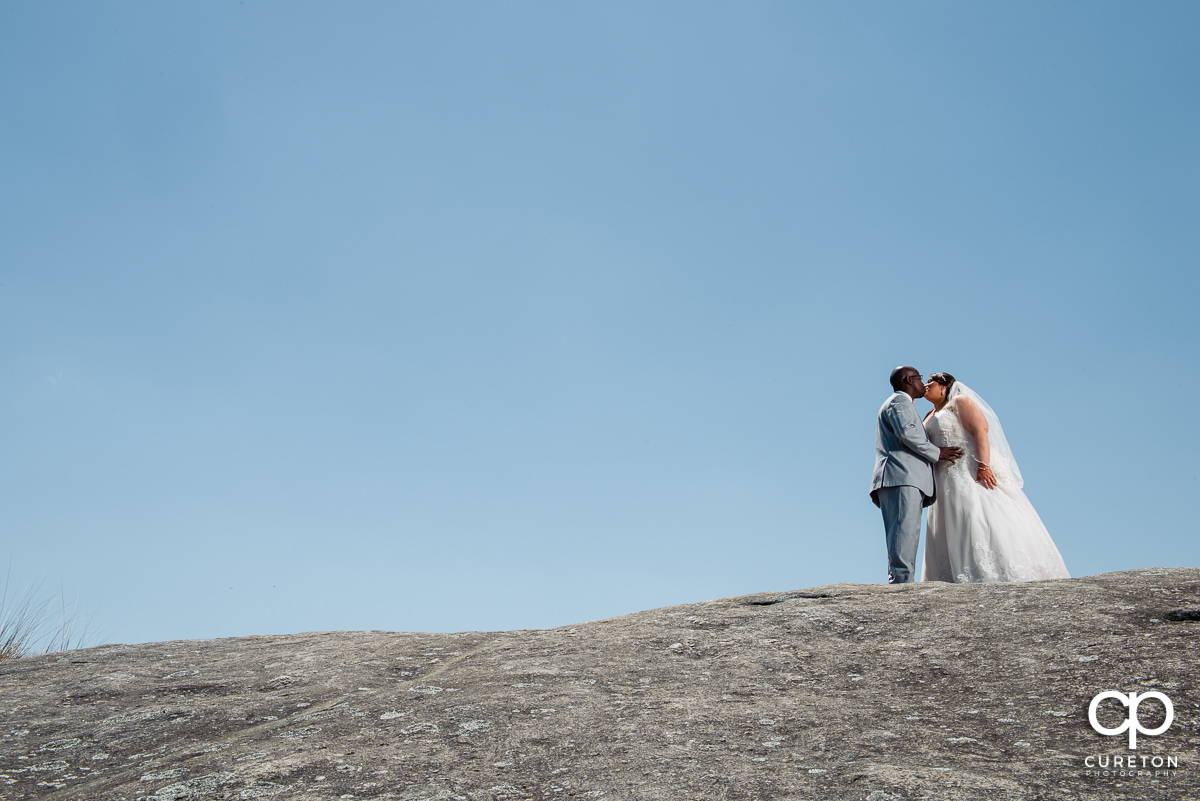 Bride and groom walking up a rock on a mountaintop at Cliffs Glassy Chapel.