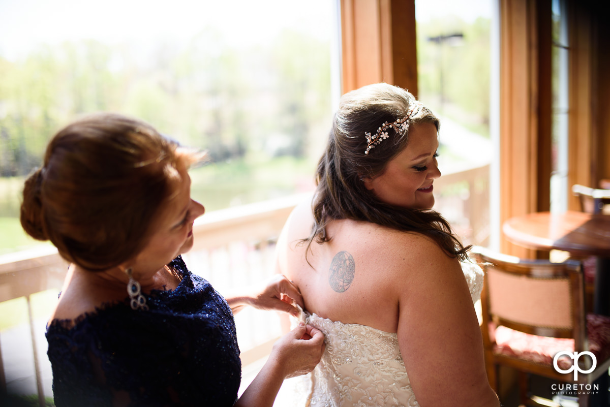 Bride putting on her dress with her mom.