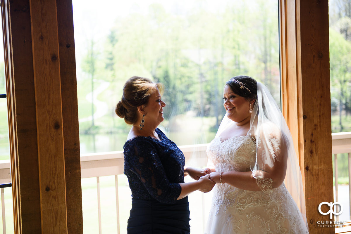 Bride and her mother standing in a window at Cliffs Glassy Clubhouse before her wedding.