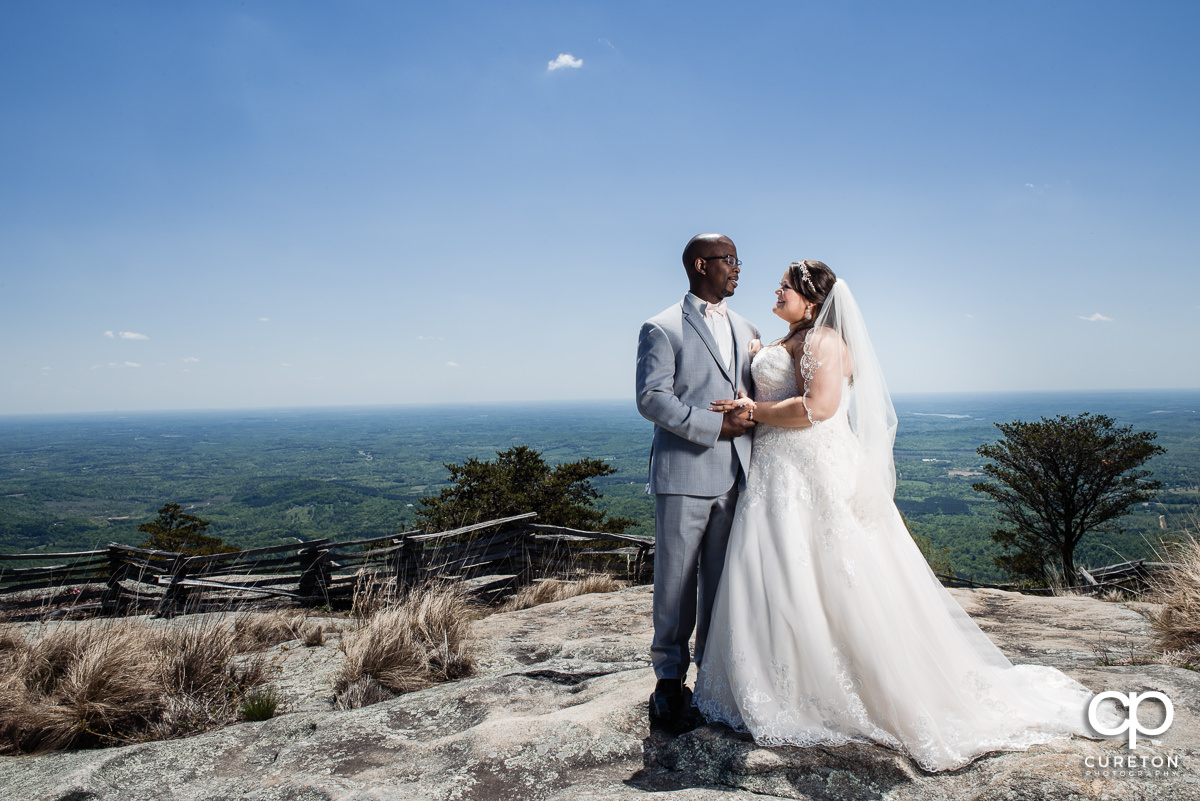 Bride and groom looking at each other on a mountain top.