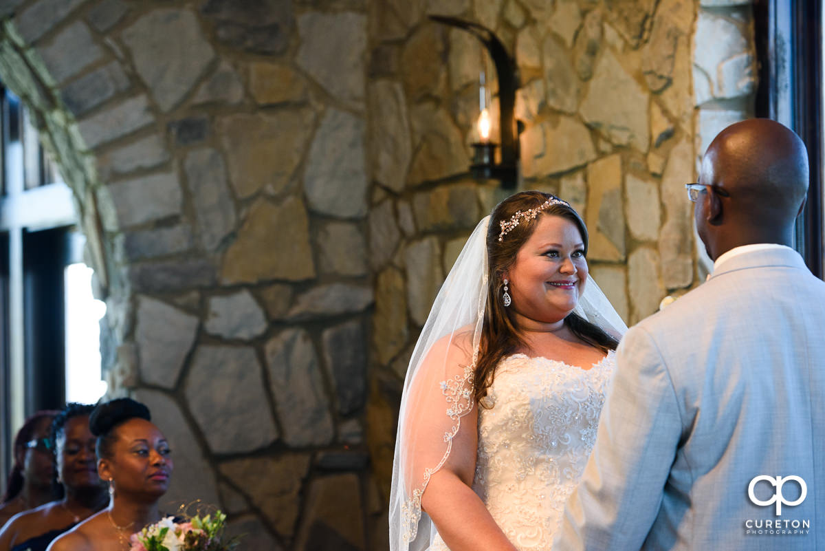 Bride smiling at her groom during the wedding ceremony at Glassy Chapel.