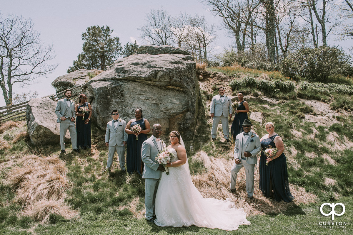 Wedding party standing by a huge rock at Glassy Chapel on a mountain top.