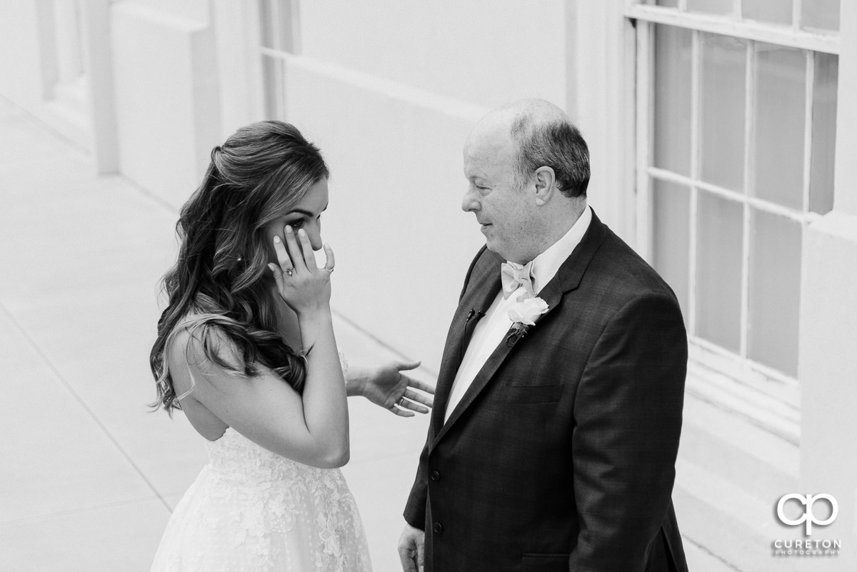 Bride wiping a tear as she sees her dad for the first tim on her wedding day.