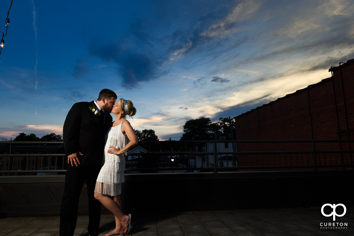 Bride and groom kissing on a rooftop in downtown Greer after outside of their Grace Hall wedding reception.