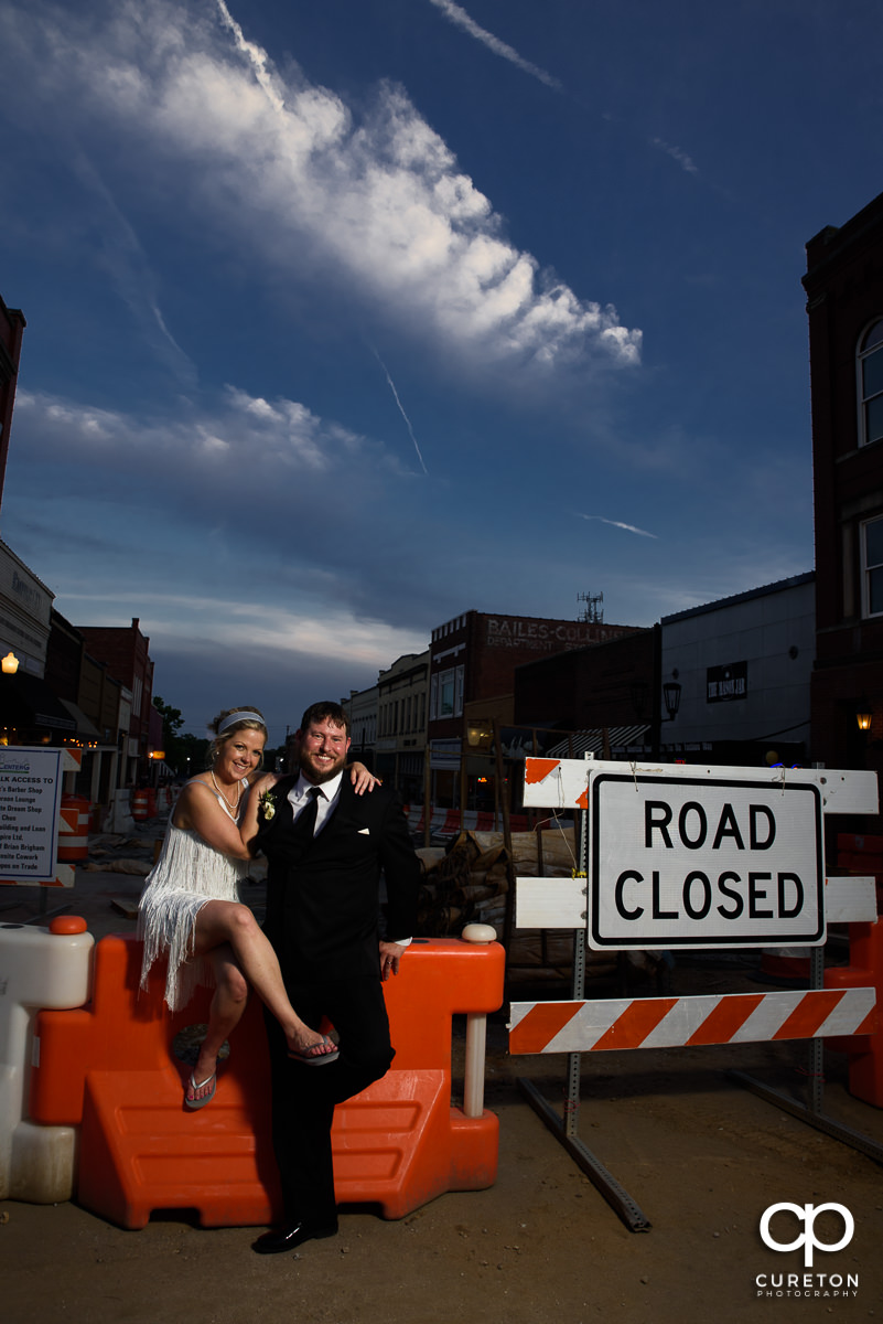 Bride and groom sitting in the middle of road construction outside of their Grace Hall wedding reception in Greer, SC.