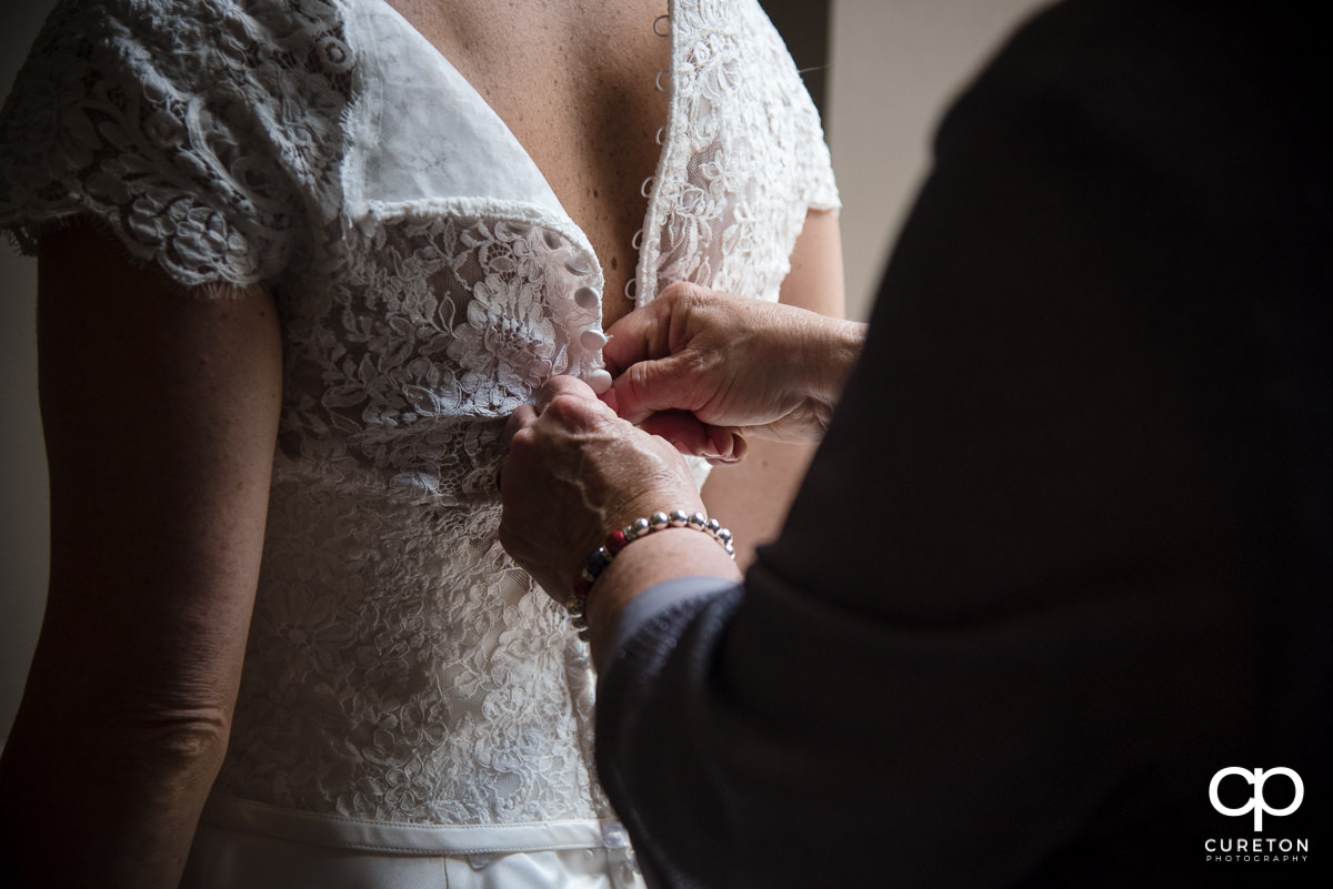 Bride fastening her dress.