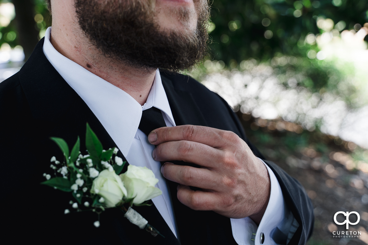 Groom fixing his tie.