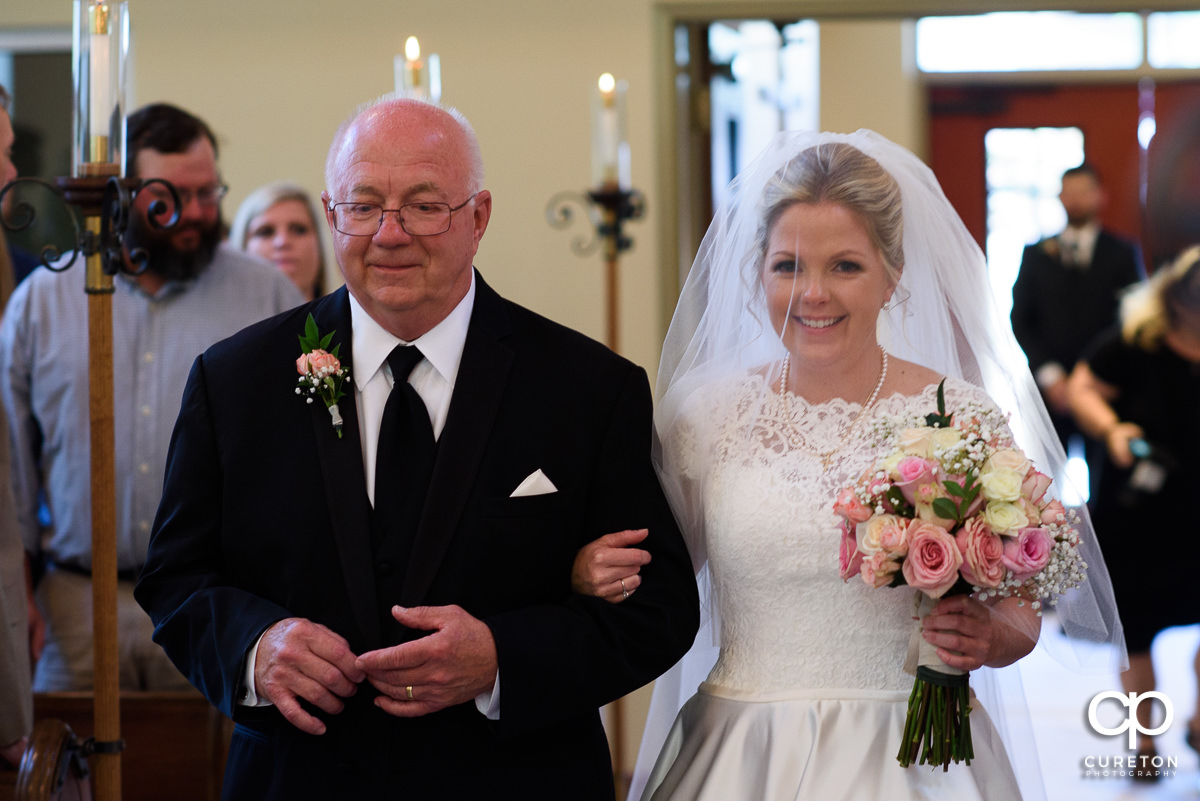 Bride and her father walking down the aisle at the wedding ceremony.