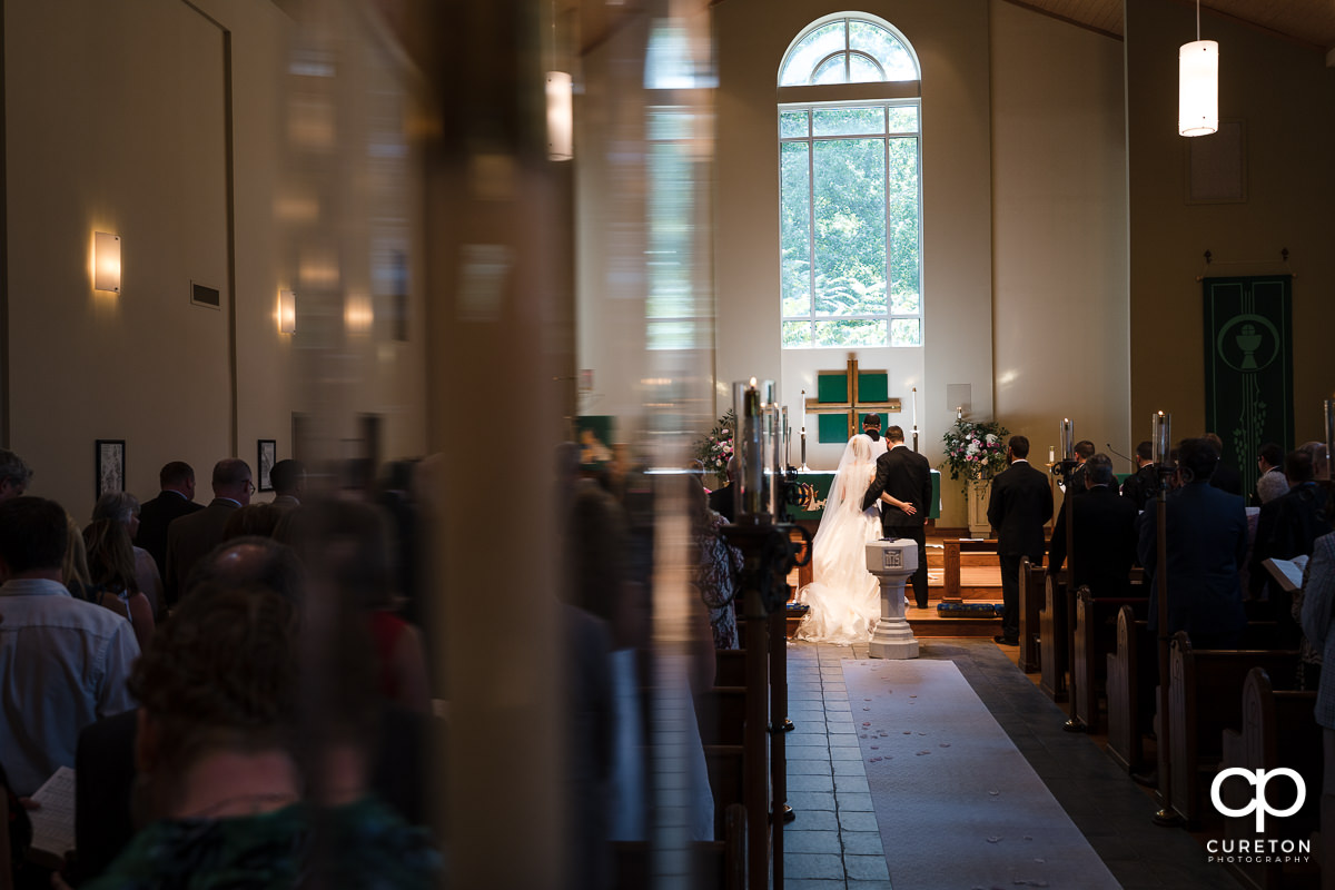 Bride and groom holding hands at the alter.