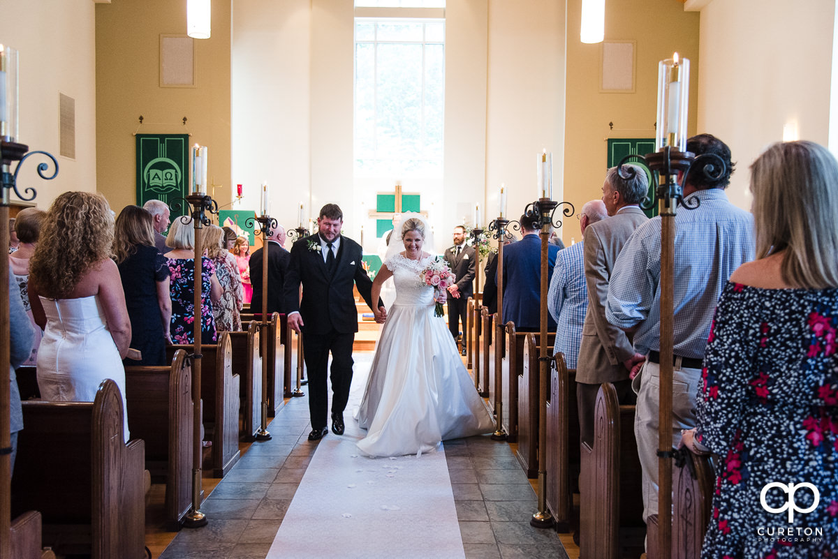 Bride and groom walking back down the aisle after being pronounced husband and wife.