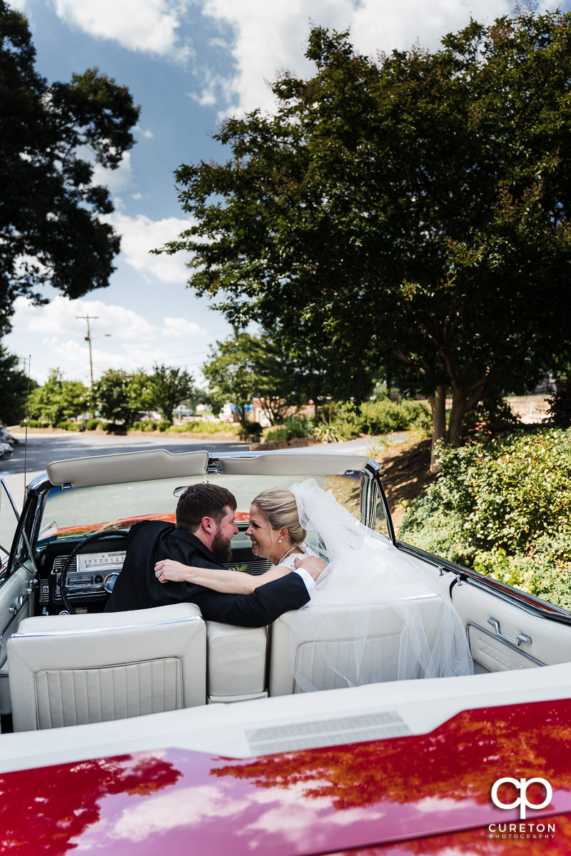 Bride and groom preparing tp leave the church in a classic Lincoln.