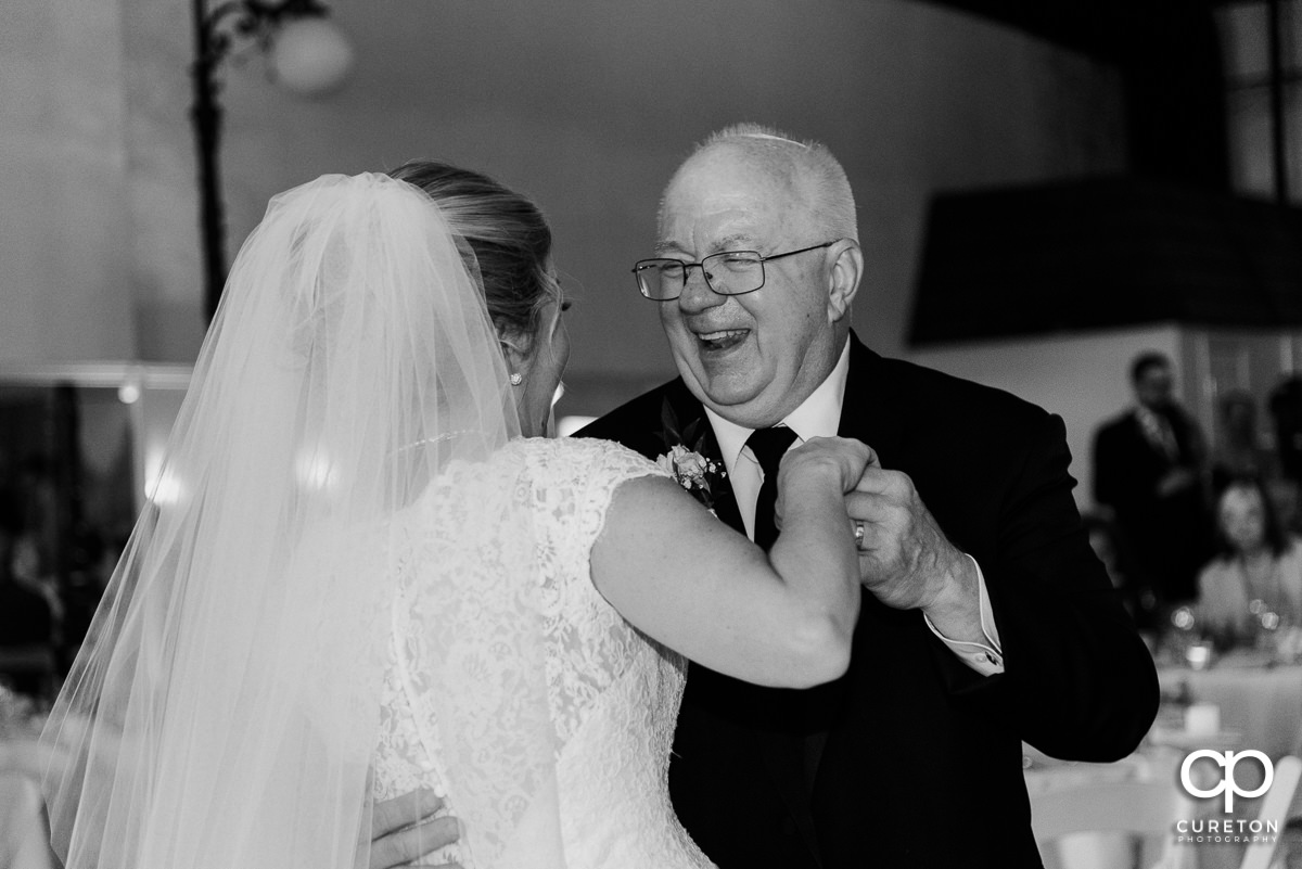 Bride's dad smiling during the first dance with his daughter at the Grace Hall wedding reception in downtown Greer,SC.