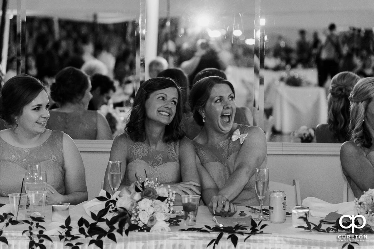 Bridesmaids smiling while watching the newlyweds dance.