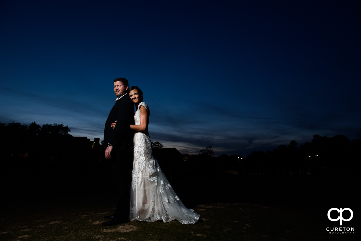 Bride holding onto her groom at sunset at their wedding reception at Green Valley Country Club.