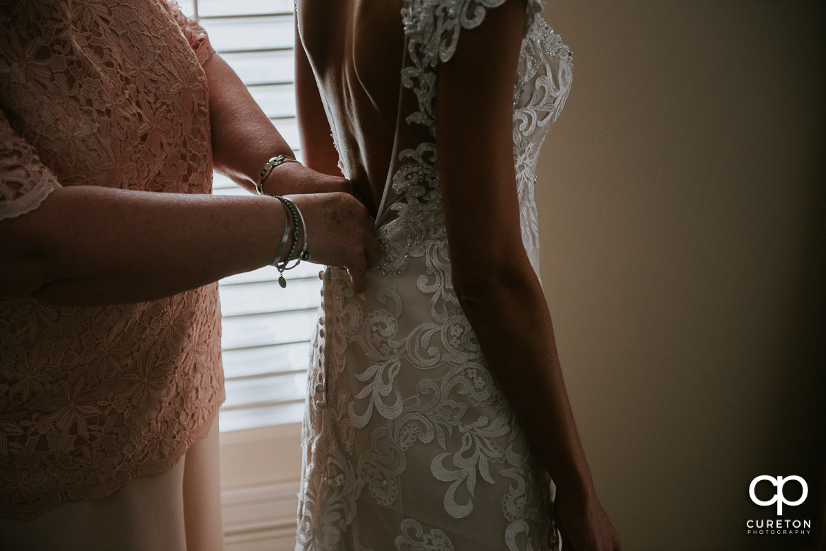 Bride's mother helping her with the back of her dress.
