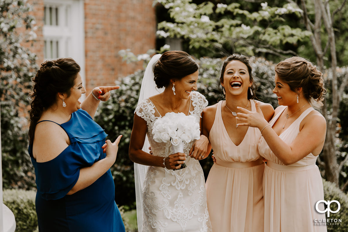 Bride and the bridesmaids laughing outside of the chapel before the wedding.