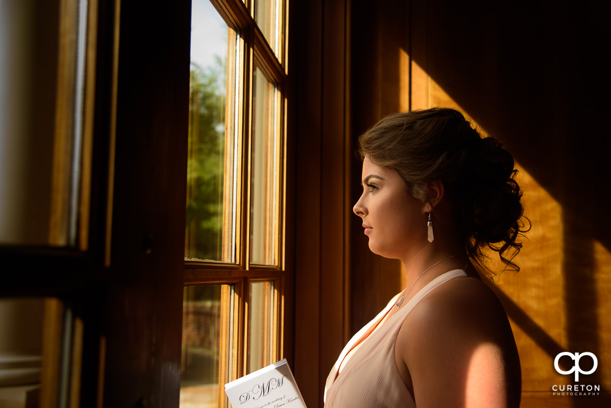 Bridesmaid staring out of a window of the chapel.