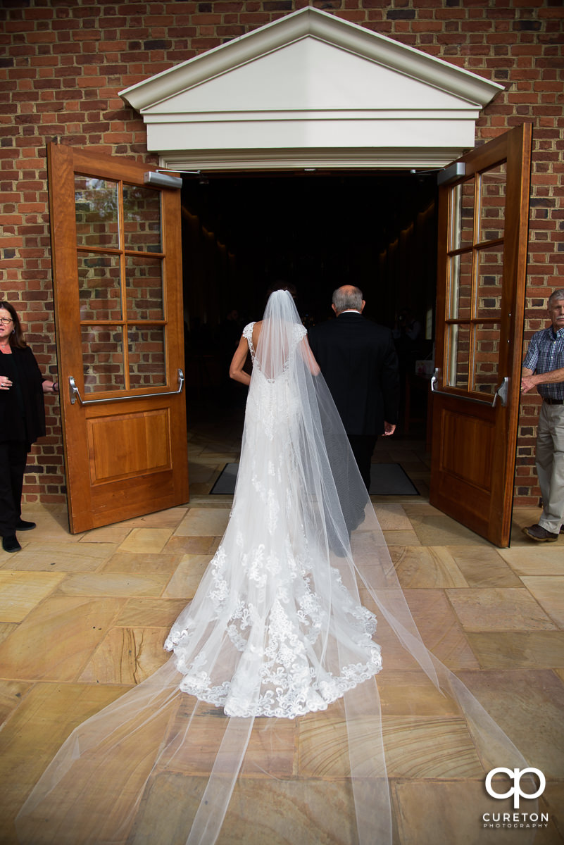 Bride walking into the chapel with her father.