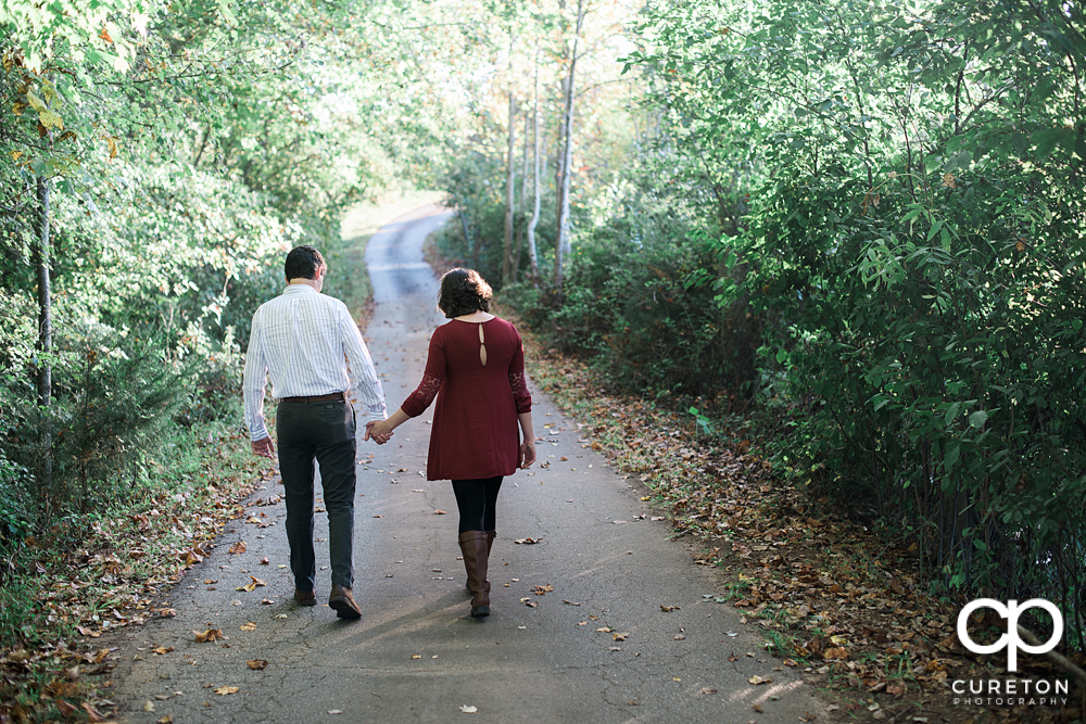Couple walking down the road during their engagement session on a farm near Greenville South Carolina.