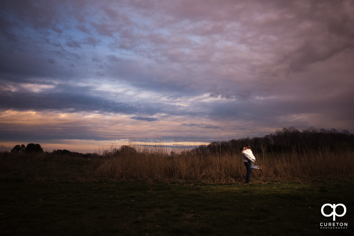 Man picking up his fiancee in a field.