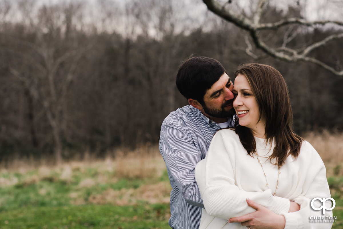 Couple snuggling during a farm engagement session.