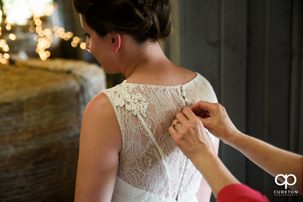 Bride's mom helping her button the dress.