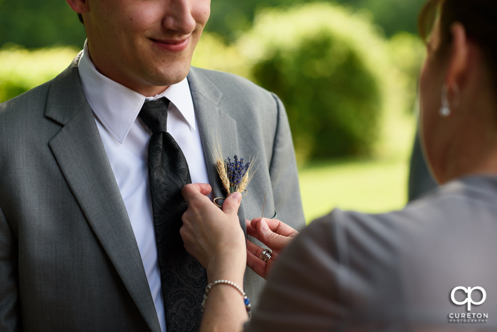 Groom getting his boutonnière pinned on.
