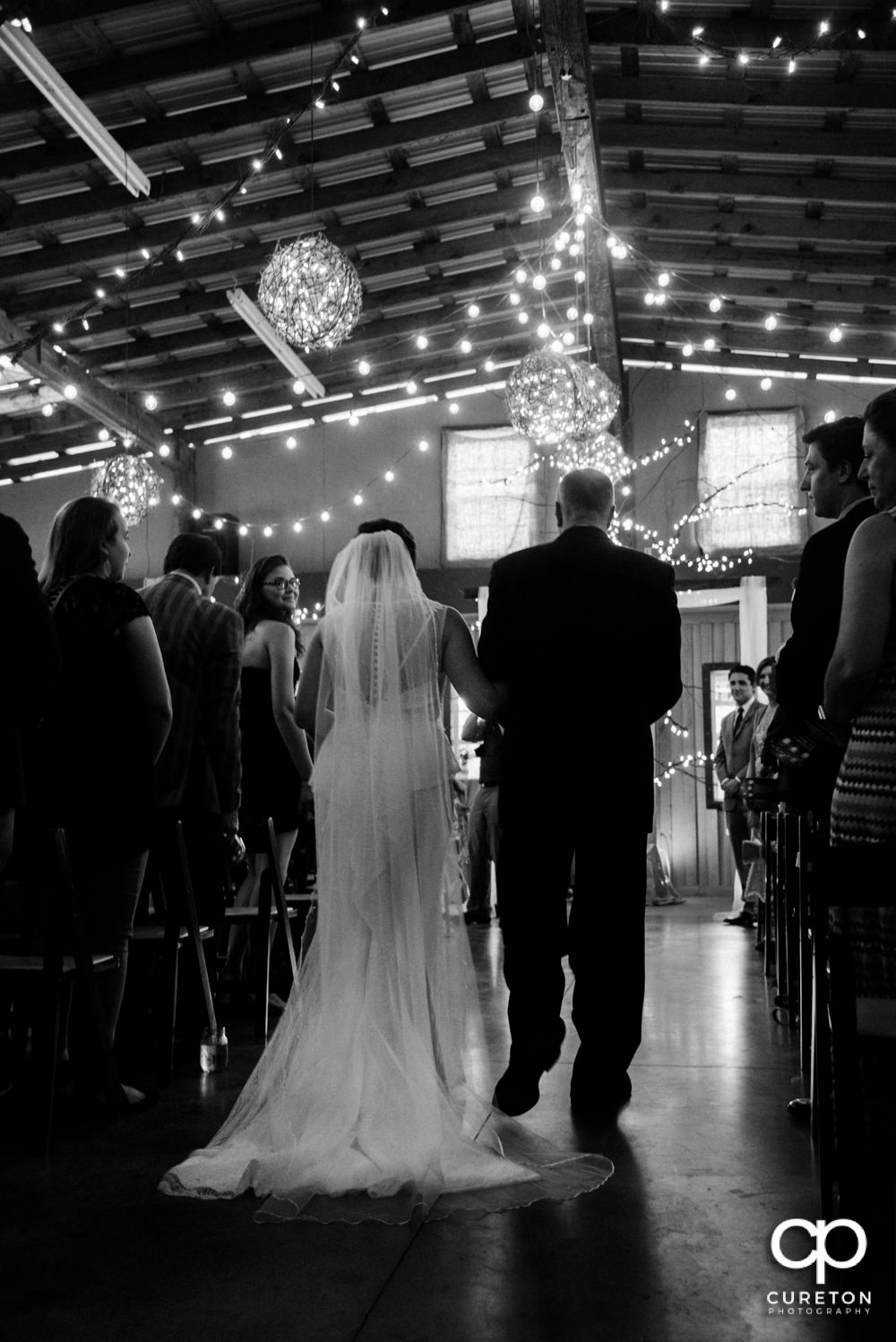 Bride and father walking down the aisle at the indoor wedding at Greenbrier Farms.