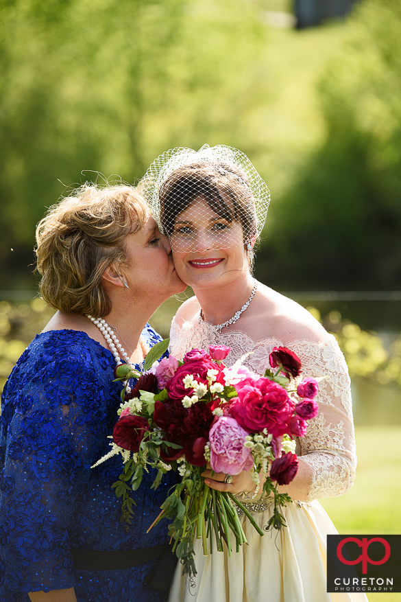 Bride's mom kissing her daughter.