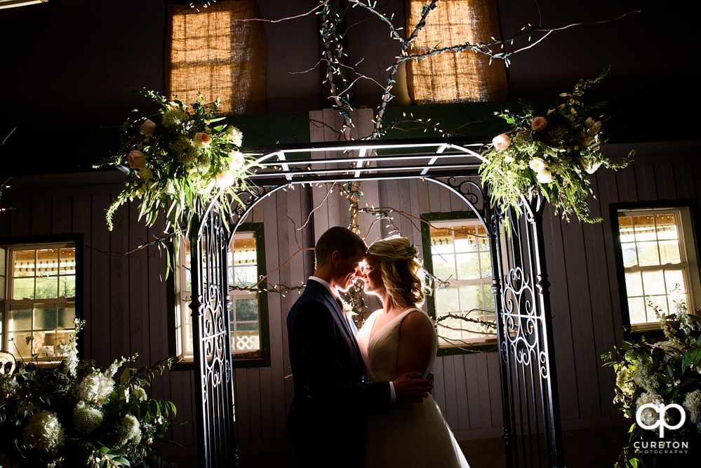 Bride and Groom kissing at the arbor at Greenbrier Farms during their wedding ceremony.