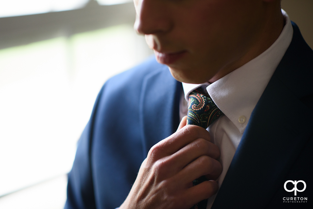 Groom adjusting his tie.