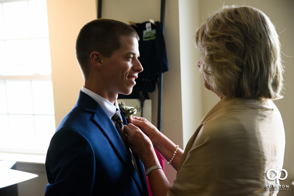 Bride's mother pinning his boutonnière.