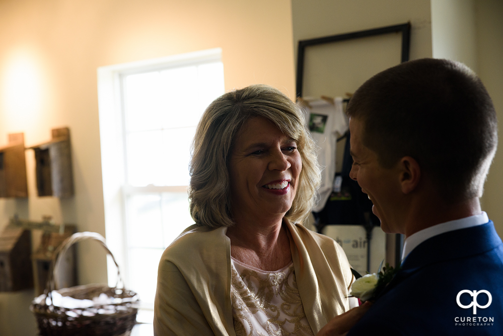 Bride's mother pinning his boutonnière.