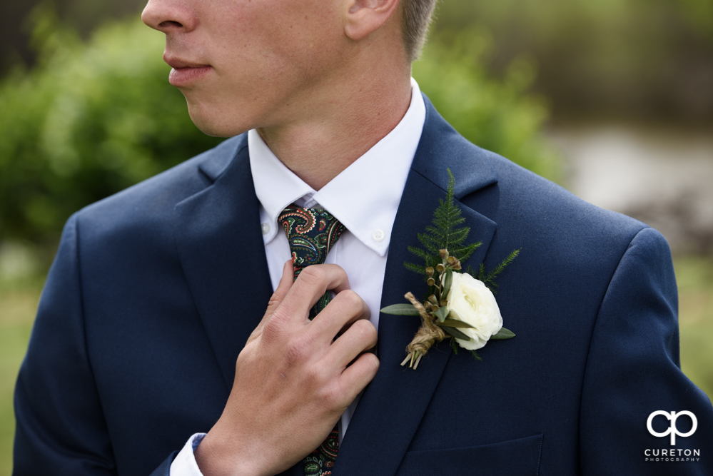 Groom fixing his tie.