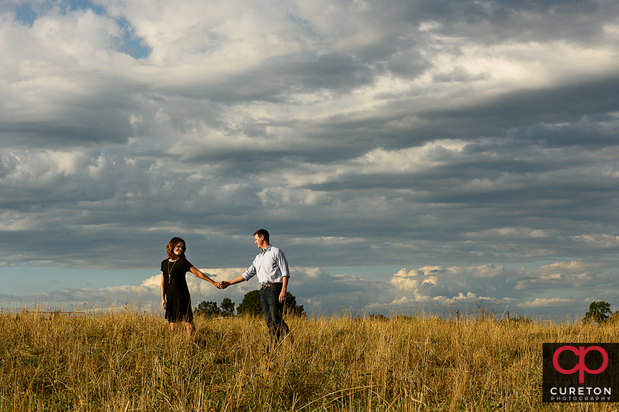 Engaged couple walking through the field during a Greenbrier Farms Engagement Session.
