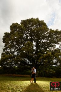Couple backlit near the huge oak tree during a Greenbrier Farms Engagement Session.