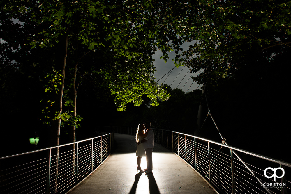 Future bride and groom kissing on Liberty Bridge during an engagement session in downtown Greenville,SC.