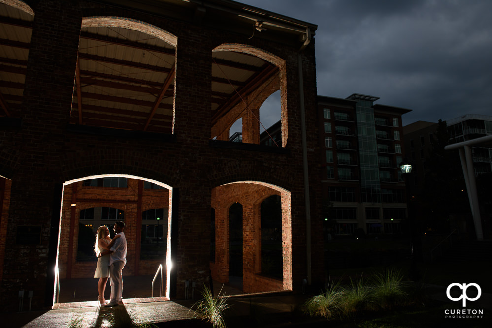 Epic photo of a couple standing in an opening of the Wyche Pavilion during an engagement session in downtown Greenville,SC.