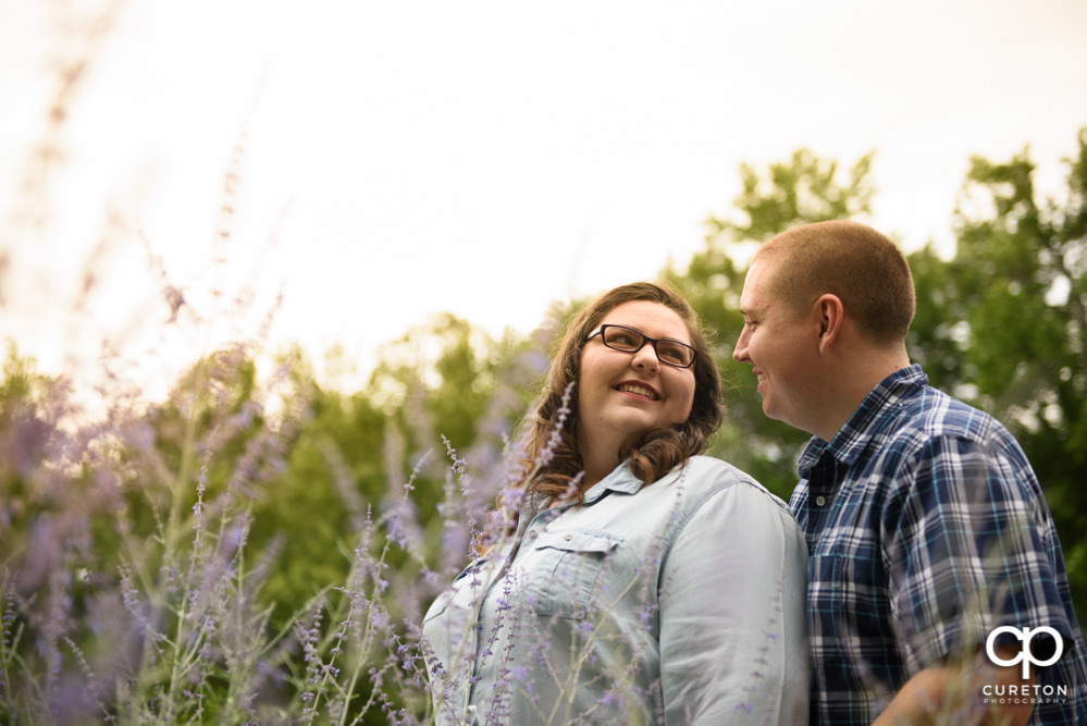 Future Bride and Groom smiling at each other in Falls Park during their engagement session with their puppy.