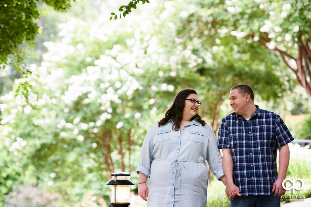 Engaged couple walking through the park.