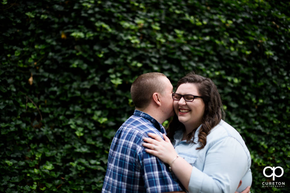 Bride laughing as groom whispers in her ear.