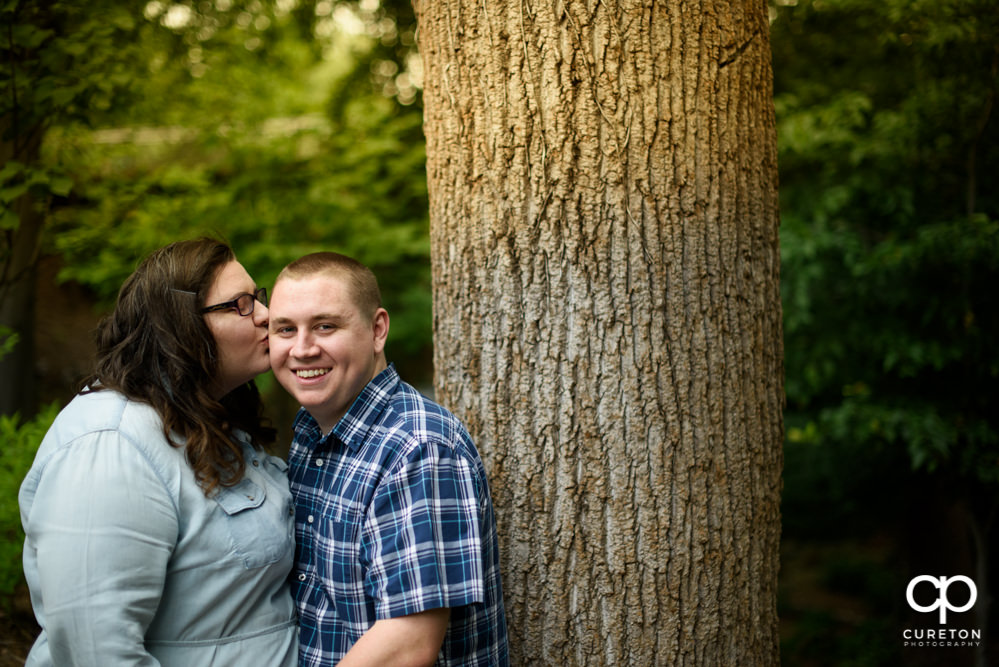 Future Bride kissing her groom on the cheek.